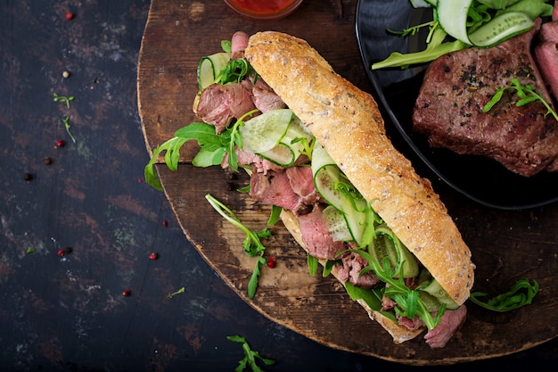 Sandwich of whole wheat bread with roast beef, cucumber and arugula. .