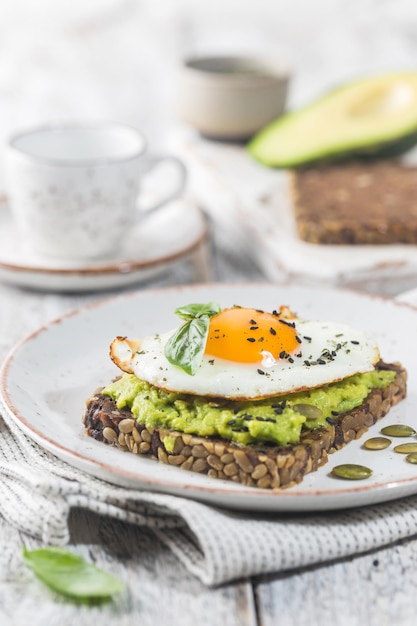 Бутерброд с яйцом авокадо и шпинатом на белом деревянном фоне здоровый диетический завтрак