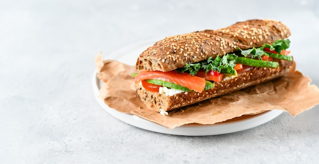 sandwich  with avocado, salmon, cream cheese, tomatoes and lettuce leaves 