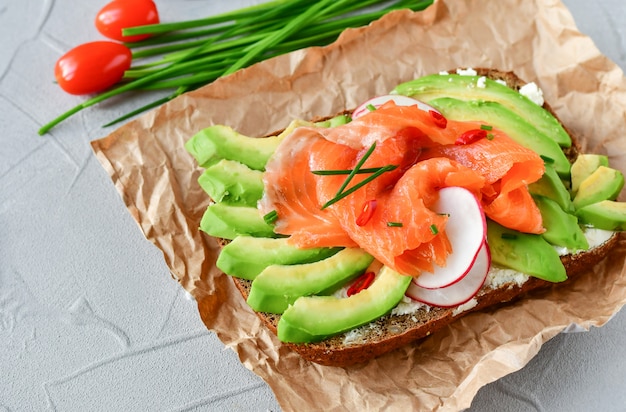 Panino con avocado e salmone su uno sfondo chiaro