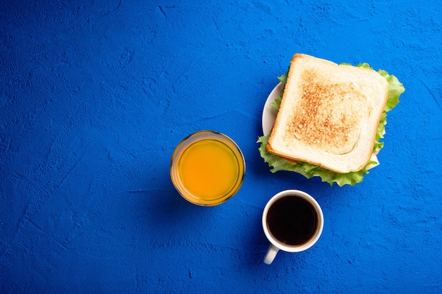 Sandwich with bacon, cheese and herbs on a blue background