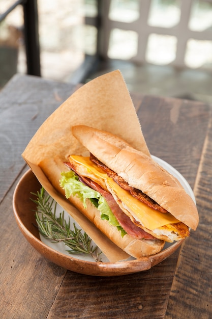 Фото Сэндвич с беконом, ветчиной, яйцом и сыром чеддер