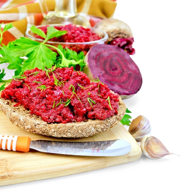 Sandwich with beet caviar and dill, knife on a wooden board, parsley, garlic, beets, napkin isolated on white background