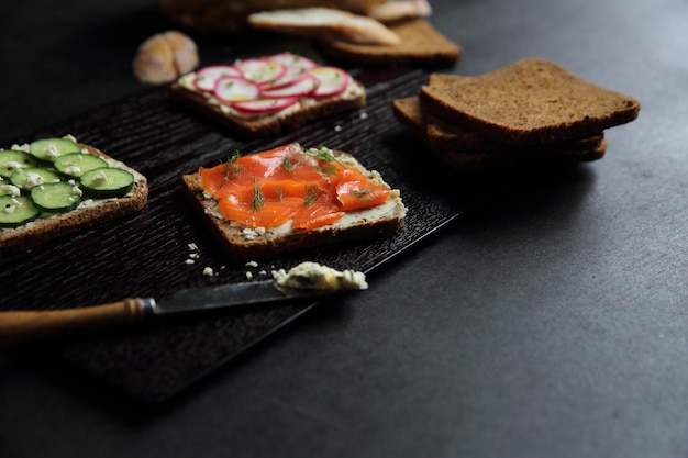 Sandwich with cereals bread smoked salmon beetroot and cucumber on dark marble background