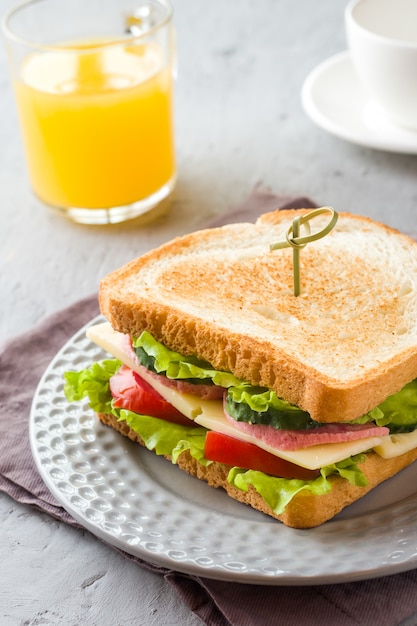 皿にチーズ、ハム、新鮮な野菜のサンドイッチ。