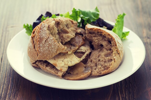 Sandwich with chicken and mushrooms on white plate