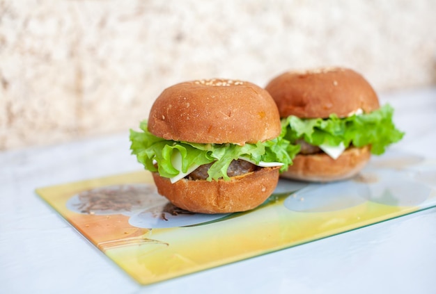 Panino con cotoletta, formaggio e insalata verde su un piatto in cucina. panino a casa. il concetto di cibo sano e malsano.