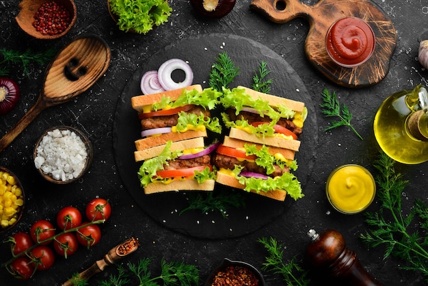 Sandwich with cutlet cheese and lettuce on a black stone background Street food Top view Free copy space