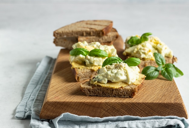 Sandwich with egg salad, avocado and hummus with basil and fresh ingredients for making sandwiches. 