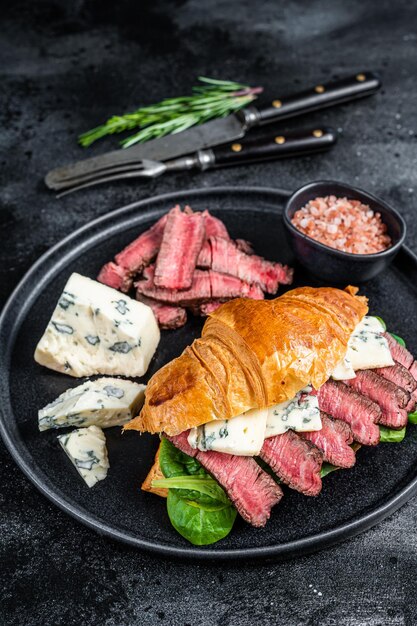 Sandwich with Fillet Mignon meat steak, Croissant and blue cheese. Black background. Top view.