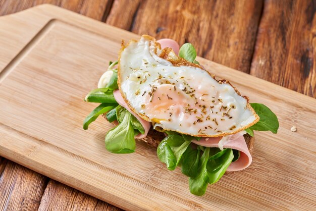 Sandwich with fried eggs and sausage on a wooden table