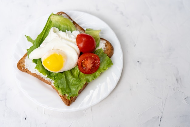 Panino con uova fritte e pomodoro su un piatto