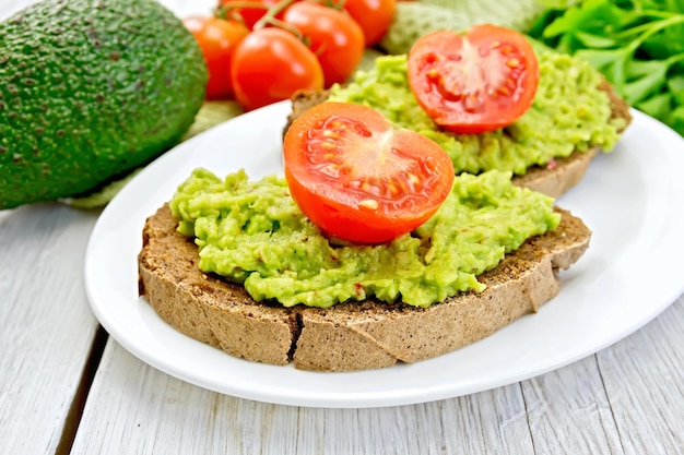 Sandwich con guacamole avocado e pomodoro su tavola leggera