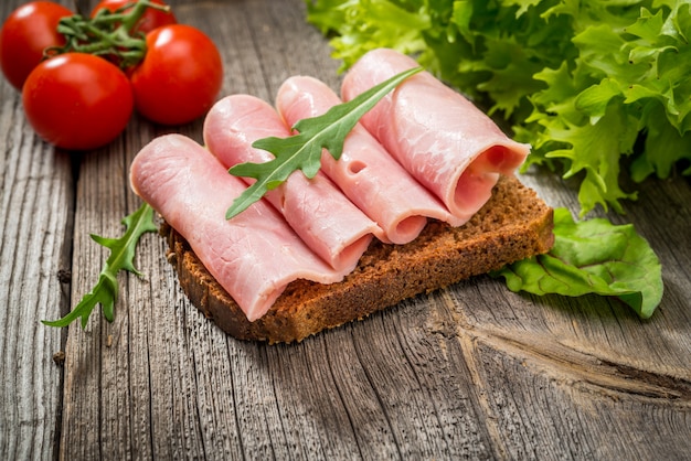 Бутерброд с ветчиной и овощами. органические продукты на деревянном столе