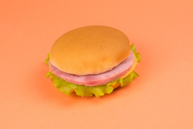 Sandwich with ham cheese lettuce on orange background
