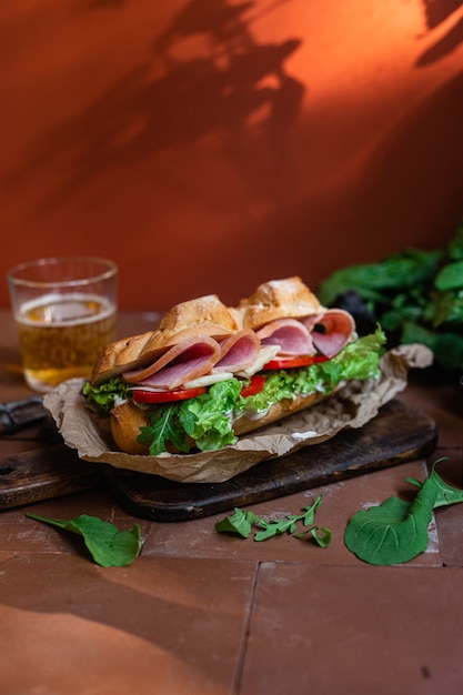 Panino con prosciutto formaggio pomodoro e lattuga su fondo scuro