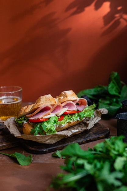 Sandwich with ham cheese tomato and lettuce on a dark background