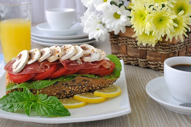 Сэндвич с ветчиной и грибами с чашкой кофе и сока