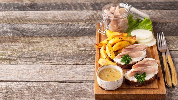 Sandwich with herring and baked potato on wooden board. 