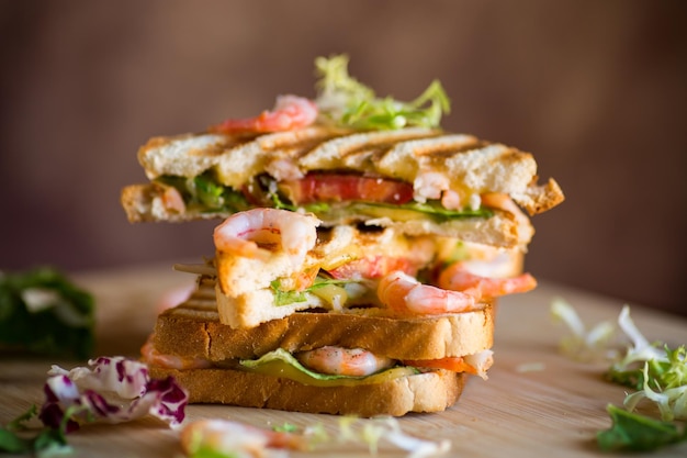 sandwich with lettuce and shrimp on a wooden board