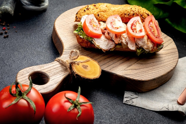 Sandwich with minced meat with herbs and tomatoes on a dark background