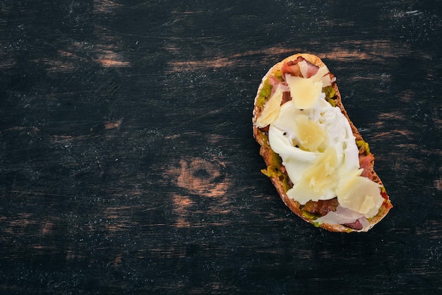 Sandwich with poached egg avocado and parmesan cheese On a wooden background Free space for text Top view