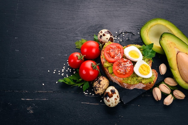 Photo sandwich with quail eggs avocados cherry tomatoes and pistachios on a wooden background top view free space for your text