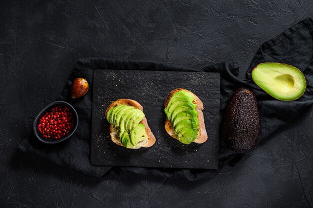 Sandwich with ripe avocado. Black background. Top view