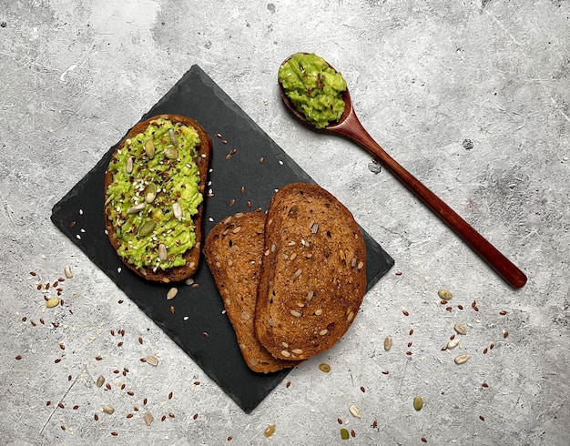 Sandwich with rye bread with cereals and avocado on light background. Top view, flat lay.