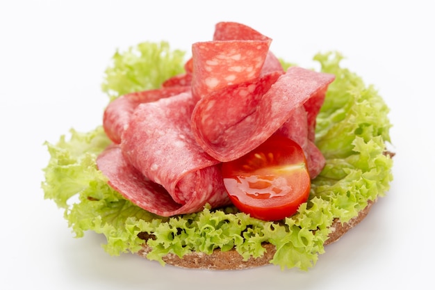 Сэндвич с колбасой салями на белом фоне.