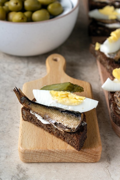 Sandwich with sardine egg pickled cucumber on a wooden board table setting