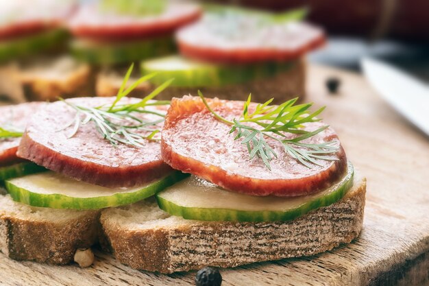 sandwich with sausage and vegetables on wooden surface