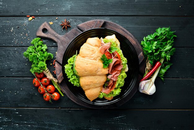 Sandwich with Slices of Prosciutto on old wooden background Croissant Breakfast Top view Free space for your text