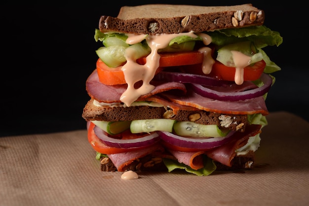 Sandwich with smoked beef, red onion, cucumber, tomatoes, lettuce, and whole grain bread. Delicious healthy lunch with meat