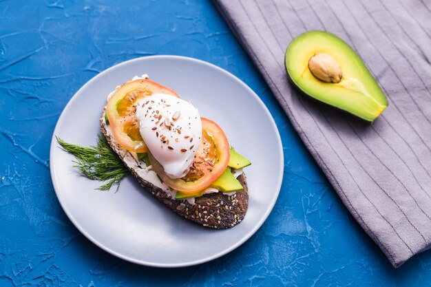 Sandwich with smoked salmon, egg and avocado on blue surface, top view. Concept for healthy nutrition.