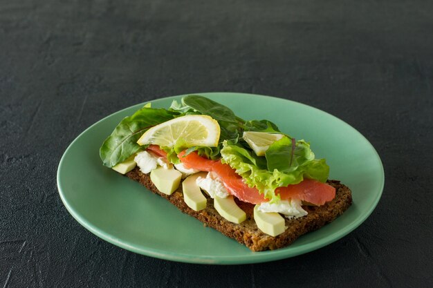Sandwich with smoked salmon soft cheese, lattice and avocado. Concept for a tasty and healthy meal. Food on a plate.