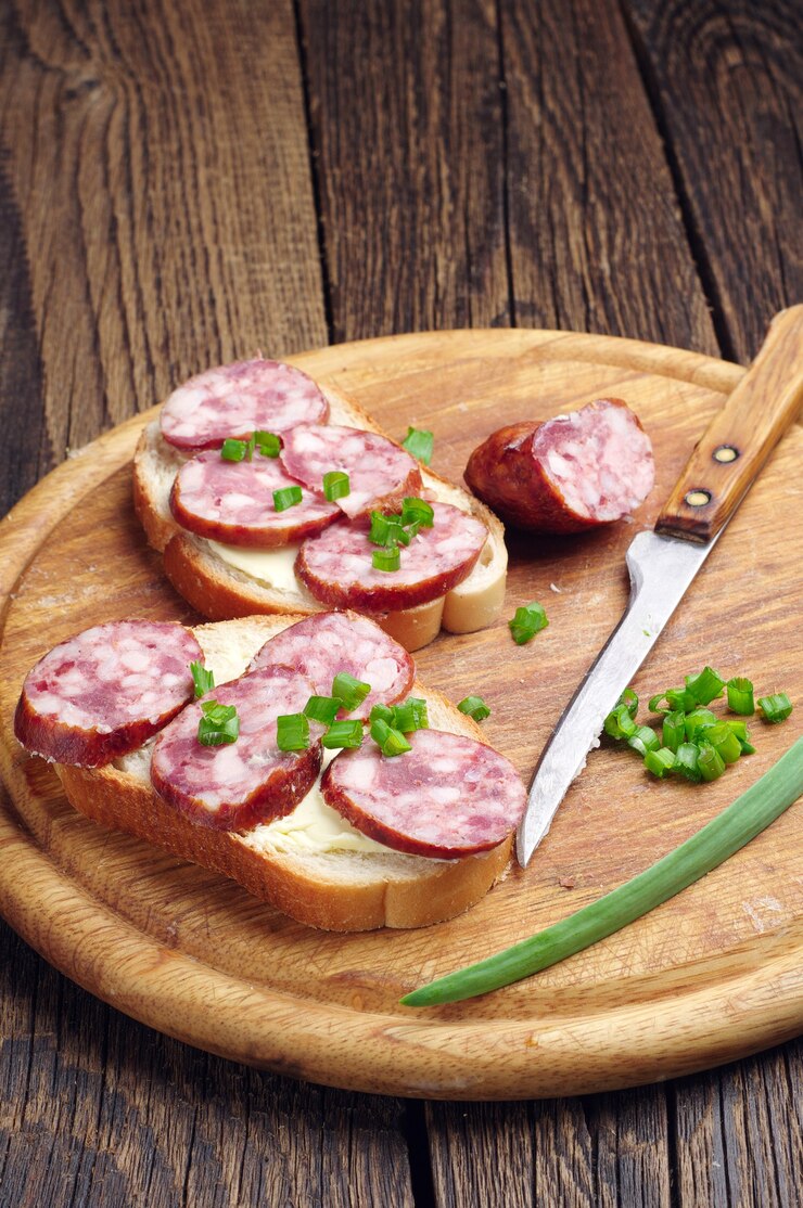 Photo sandwich with smoked sausage and green onion on a round cutting board