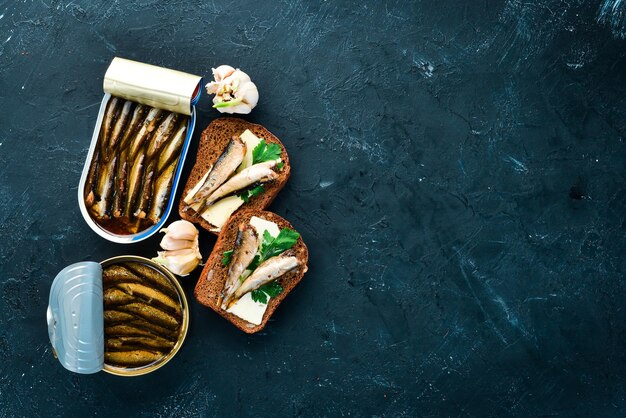 Sandwich with Sprat Sprat in oil On a black background top view Free copy space