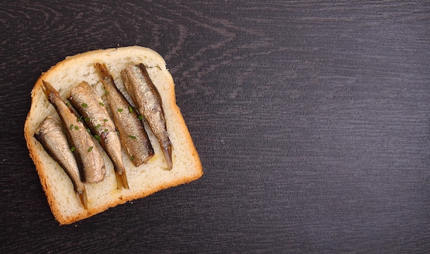 Бутерброд со шпротами на черном фоне