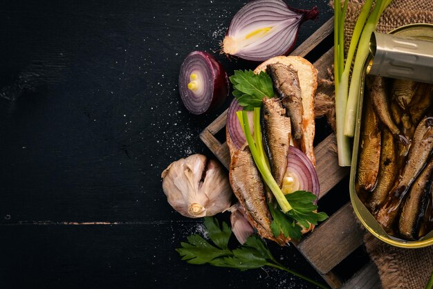 Sandwich with sprats onions and parsley on a wooden background Top view Copy space