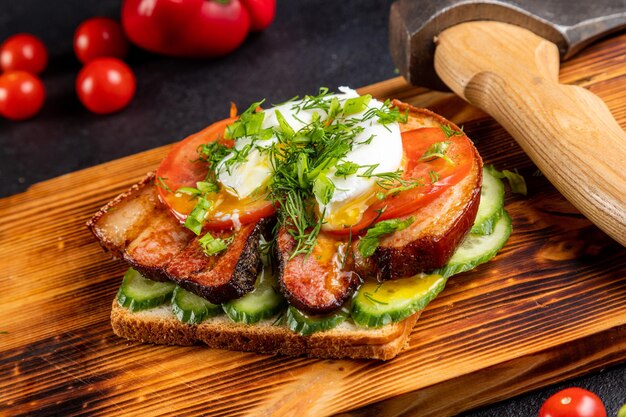 Sandwich with steak and vegetables, served on a derephone board. dark background decorated with food