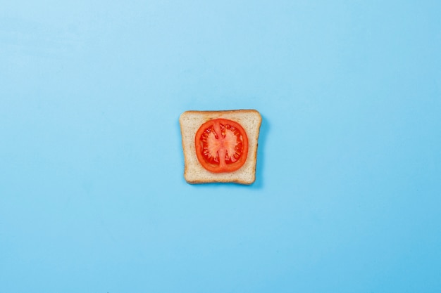 Sandwich with tomato on a blue surface. Concept of diet, healthy eating, losing weight. Flat lay, top view.