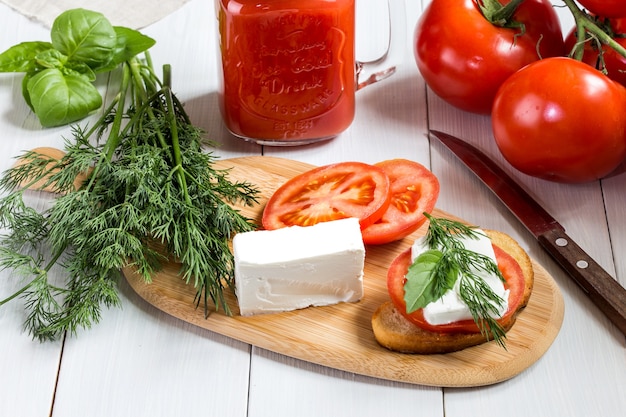 A sandwich with tomato, cheese and herbs