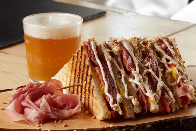 Sandwich on a wood tray with a beer 