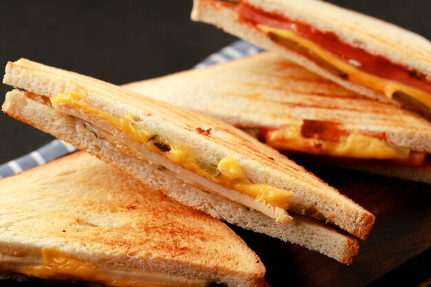 Sandwiches cut into halves on wooden cutting board with napkin on table