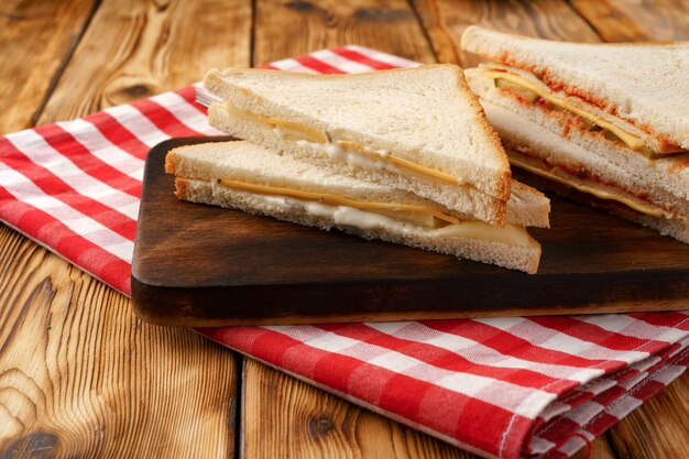 Sandwiches cut into halves on wooden cutting board with napkin