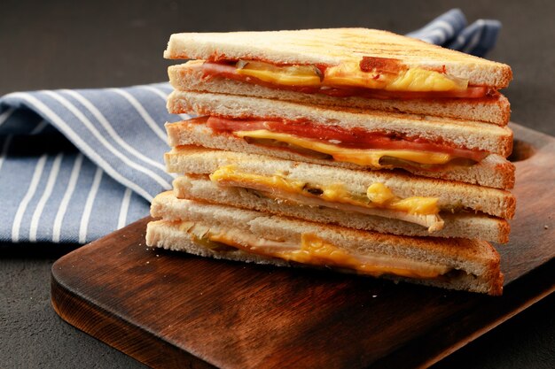 Sandwiches cut into halves on wooden cutting board with napkin