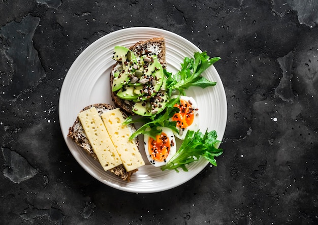 Sandwiches met avocadokaaszaden en gekookt ei heerlijk ontbijtsnack op een donkere achtergrond bovenaanzicht