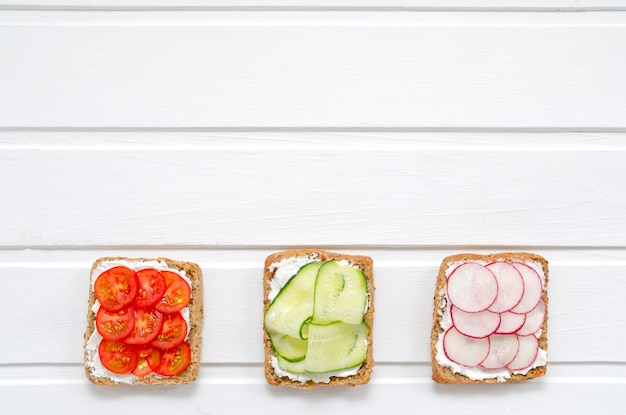 Foto sandwiches met een sneetje volkoren donker brood roomkaas komkommers radijs cherrytomaatjes