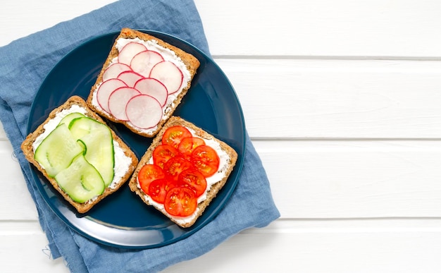 Foto sandwiches met een sneetje volkoren donker brood roomkaas komkommers radijs cherrytomaatjes
